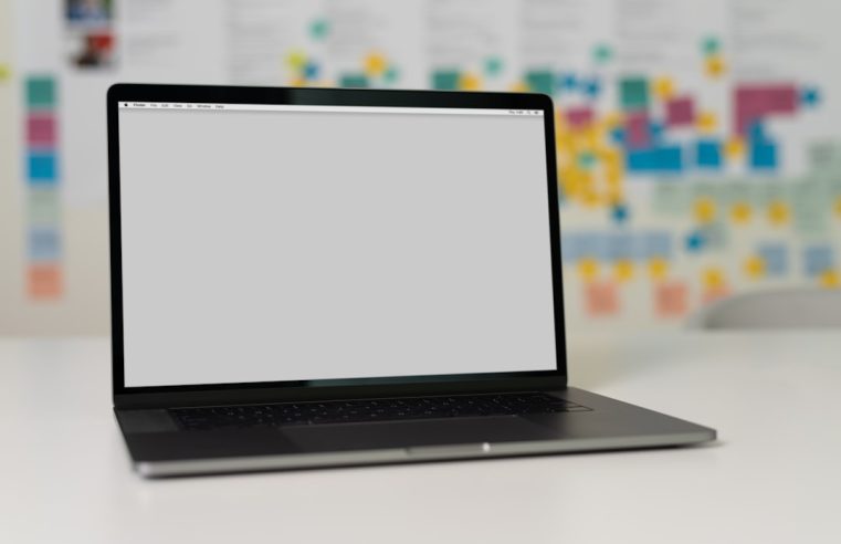 A laptop on a table with a blurred background of colorful sticky notes.